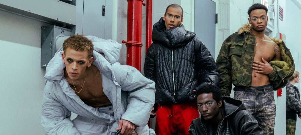 Four individuals in various outfits in a room with a fire extinguisher.